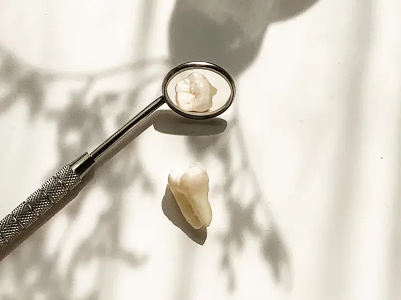 Dental mirror reflecting an extracted tooth, with a second tooth beside it
