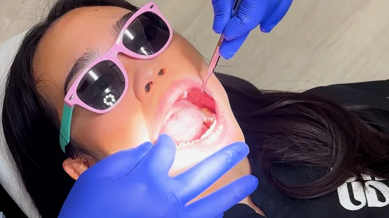 Patient in pink sunglasses having an oral examination at University District Dental